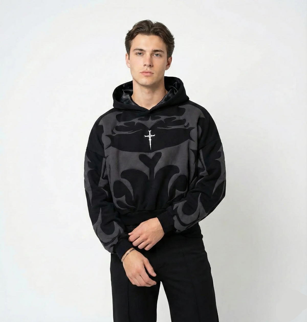 Young man wearing a black graphic streetwear hoodie with bold abstract patterns