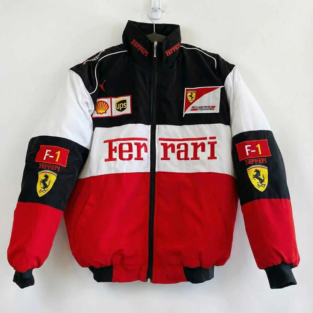 Red, black and white Ferrari F1 racing jacket with sponsor patches and logos, front view.