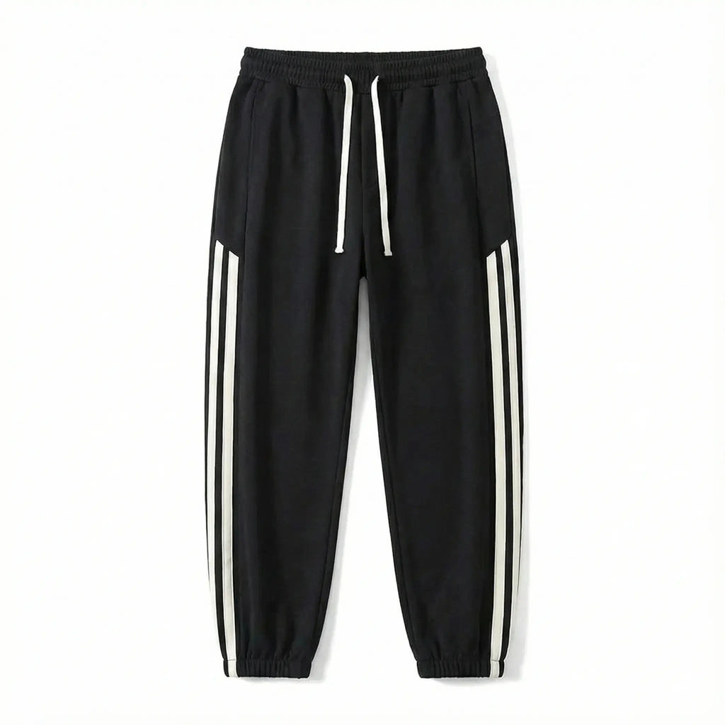 Black streetwear jogger pants with white side stripes and drawstring waist on white background