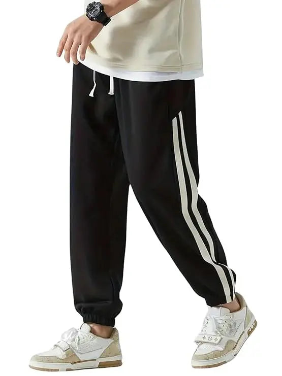 Men's black track pants with white side stripes and drawstring waist, streetwear style.