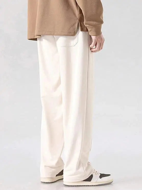 back view of person wearing loose cream trackpants and white sneakers, casual streetwear style